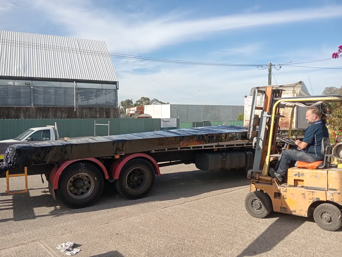 Wrapped steel patio kit being loaded by forklift onto a flatbed delivery truck at the Patio & Shed Kits WA dispatch facility